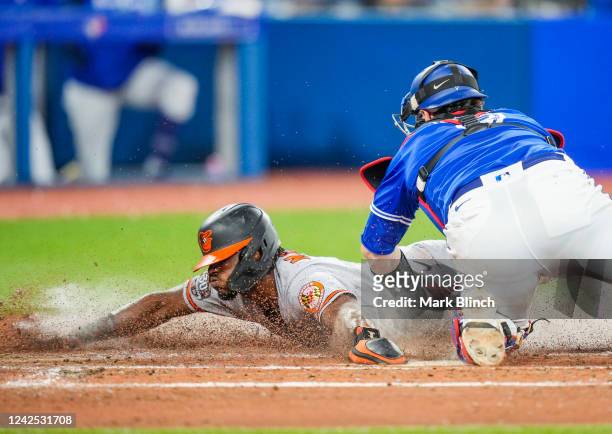 Jorge Mateo of the Baltimore Orioles scores past Danny Jansen of the Toronto Blue Jays in the fourth inning at the Rogers Centre on August 15, 2022...