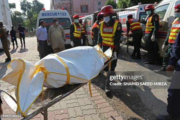 Members of Rescue 1122 team, shift a burnt body of a victim to a hospital following an overnight collision between a passenger bus and an oil tanker...