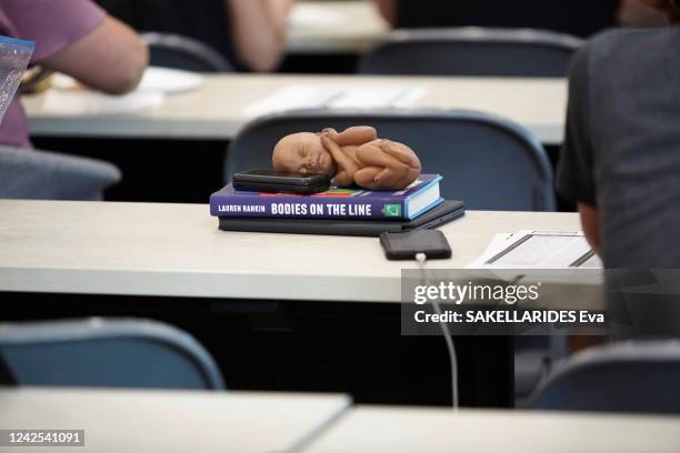 On a desk, placed on a pro-abortion book, a doll very much used by the anti-abortion pro-lifers: they claim that it represents a 12 weeks old fetus....