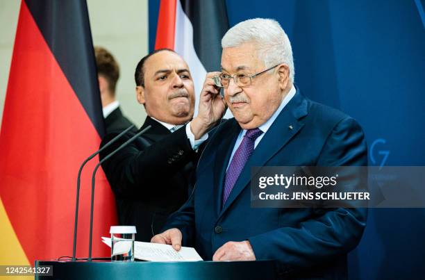 Palestinian President Mahmud Abbas is helped with the headphones at the start of a joint press conference with Germany's Chancellor at the...