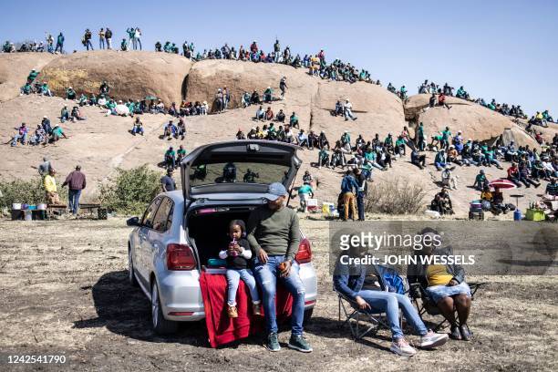 Family sits at their car as people gather on the koppies in Marikana on August 16 during the 10th anniversary of the Marikana massacre. - August 16,...