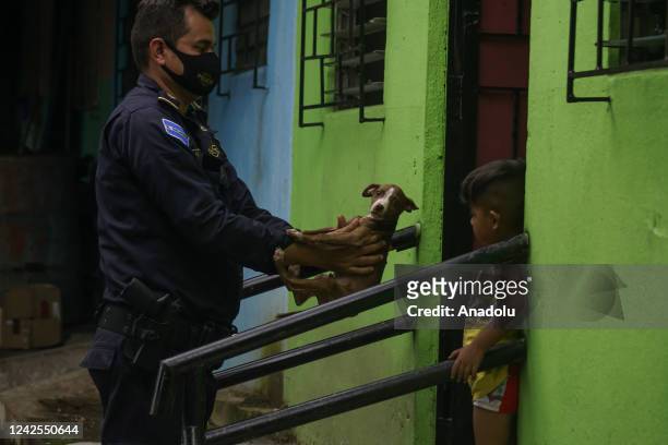 An agent of the National Civil Police delivers a puppy to a child, during an operation in neighborhoods of the municipality of Soyapango, in San...