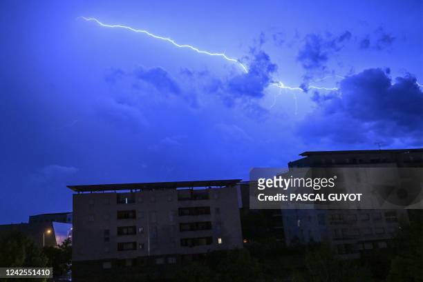 In this photograph taken on August 16, 2022 lightning strikes over residential buildings during a thunderstorm in Montpellier.