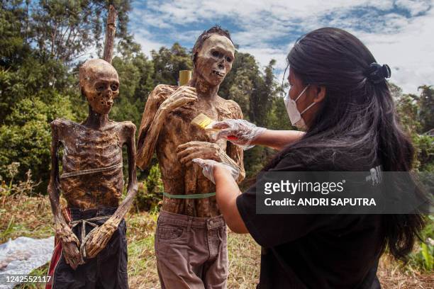 This picture taken on August 17, 2022 shows a family member of the Toraja ethnic group preparing the bodies of exhumed relatives from a community...