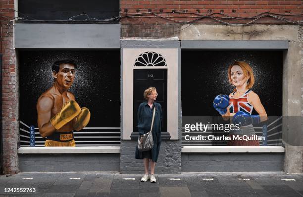 Member of the public is seen standing in front of a mural depicting Conservative party leader hopefuls Rishi Sunak and Liz Truss on August 17, 2022...