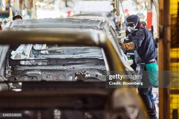 Worker attends to a steel automobile chassis on the production line at the Toyota Motor Corp. Manufacturing plant in Durban, South Africa, on...