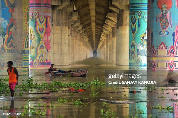Men rest on a boat in the overflowed Ganges River under the Shastri Bridge in Allahabad on August 17 as water levels of the Ganges and Yamuna rivers...