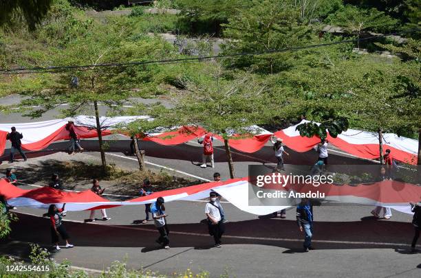 Environment activists carry the Indonesian flag with a length of 77 meters around the tallest Jesus statue in the world with a height of 1,700 meters...