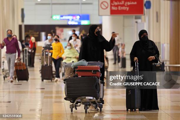 Travellers walk at Dubai Airport terminal 3, in the Gulf emirate of Dubai, on August 16, 2022. - Dubai International Airport, a major aviation hub,...