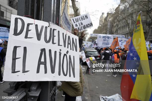 People hold banners next to a Venezuelan flag demanding the returning of an EMTRASUR cargo plane and the freedom of the crew that was held under...