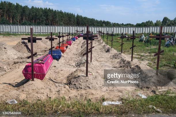 Coffins and graves are seen at a cemetery during a mass burial ceremony for 21 unidentified persons killed by Russian troops in the Bucha town close...