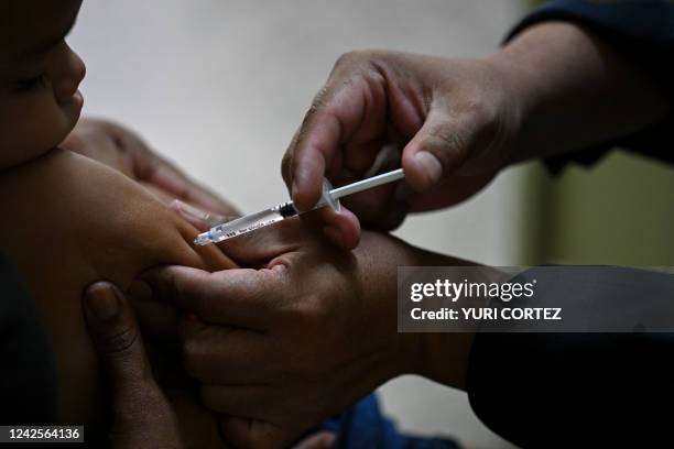 Child accompanied by his mother receives a dose of the measles and rubella vaccine from medical personnel at a community health center in the Lidice...