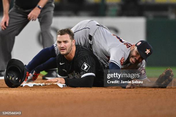 Jose Altuve of the Houston Astros falls and Adam Engel of the Chicago White Sox looks back to first base after Engel successfully broke up a double...