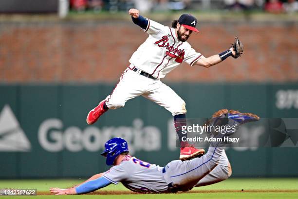 Pete Alonso of the New York Mets slides under Dansby Swanson of the Atlanta Braves during the ninth inning at Truist Park on August 17, 2022 in...