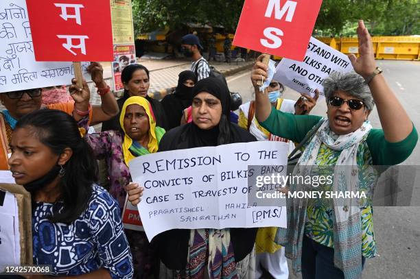 Activists shout slogans and hold placards during a protest against the release, following a recommendation by a Gujarat's state government panel, of...