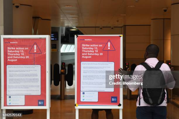 Commuter looks at signs with information about strike action, during the latest round of rail strikes, at the entrance to Waterloo East railway...