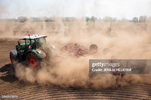 Tractor with an agricultural implement attached drives across a parched field as it raises a cloud of dust near Beelitz, eastern Germany, on August...