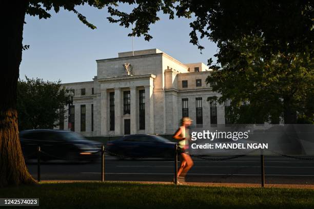 Jogger runs past the US Federal Reserve in Washington, DC on August 18, 2022. - US central bankers remain committed to raising interest rates further...