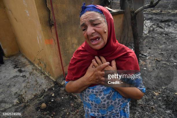 An elderly Algerian woman reacts in front of the ruins of her home, destroyed in a wildfire in the city of el-Kala, on August 18, 2022. - Algerian...
