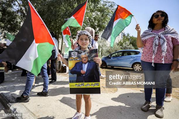Child holds a poster of Mahmud Abbas and others wave Palestinian flags as they welcome the Palestinian president in the city of Ramallah in the...