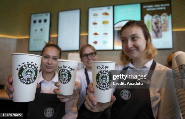 Workers of the Stars Coffee show coffee cups with logo of Stars Coffee after former Starbucks coffee shops are reopened as Stars Coffee in Moscow,...