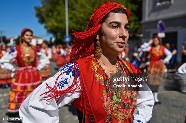 Hundreds of women dressed in traditional folk clothing from their regions walk together carrying their family gold during the Mordomia Parade part of...