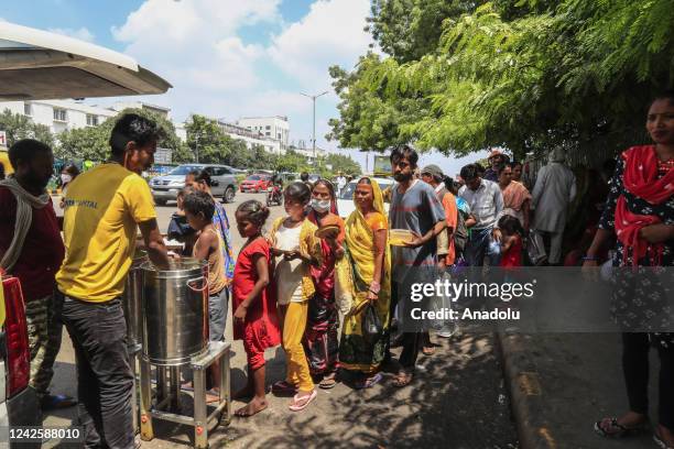 New Delhi, INDIA Patients and their families member holding bowls and pots, queue to receive food aid at the outside the All India Institute of...