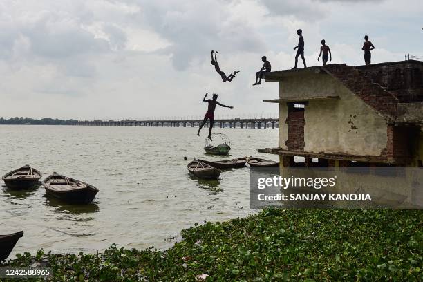 Youths jump from a partially submerged home into the overflown Ganges River in the Jushi area in Allahabad on August 19 after water level rose...