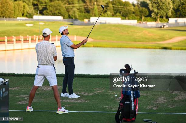 Scottie Scheffler checks his driver alignment as his caddie Ted Scott FaceTimes his coach on the practice range following the first round of the BMW...