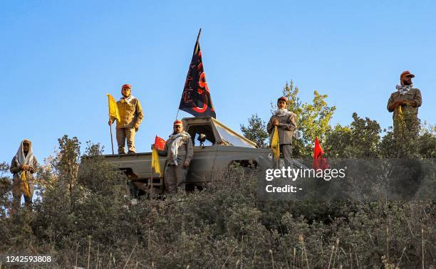 Fighters from the Lebanese Shiite Muslim movement Hezbollah pose with their group's flags and flags bearing the names of venerated Shiite Muslim...