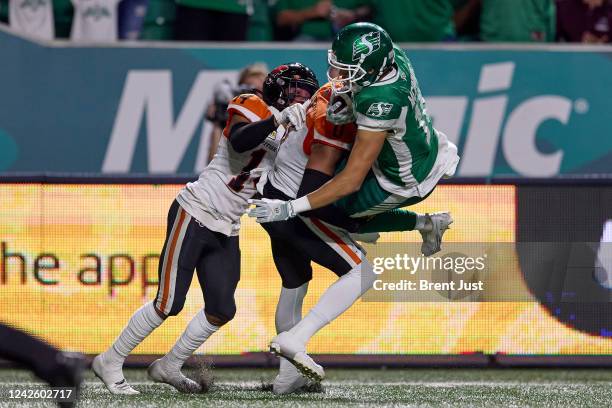 Justin McInnis of the Saskatchewan Roughriders is tackled at the end of a run by Loucheiz Purifoy and Marcus Sayles of the BC Lions in the game...