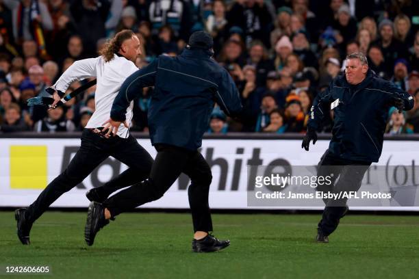 Security chase a streaker during the 2022 AFL Round 23 match between the Port Adelaide Power and the Adelaide Crows at Adelaide Oval on August 20,...