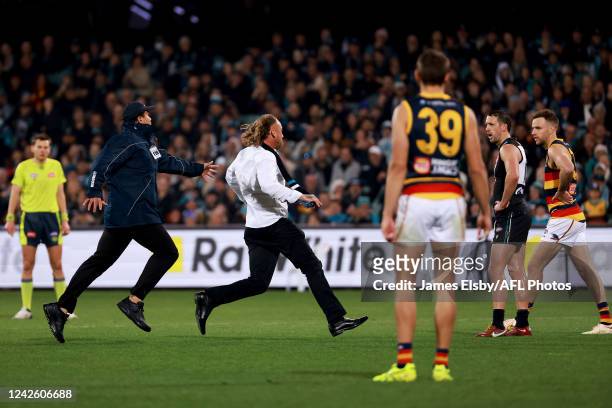 Security chase a streaker during the 2022 AFL Round 23 match between the Port Adelaide Power and the Adelaide Crows at Adelaide Oval on August 20,...