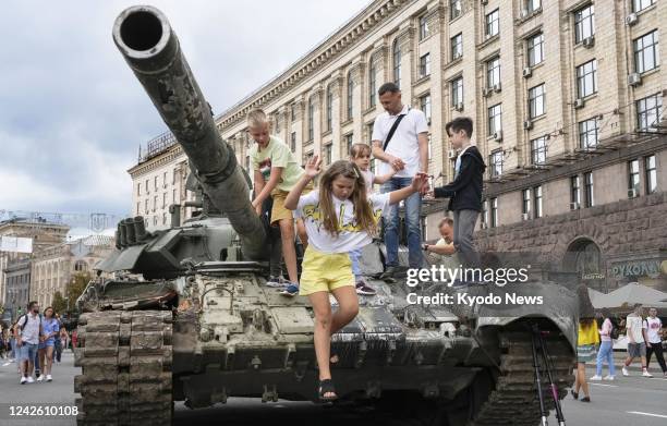 Children play on a destroyed Russian tank put on display in a square in Kyiv on Aug. 20, 2022.