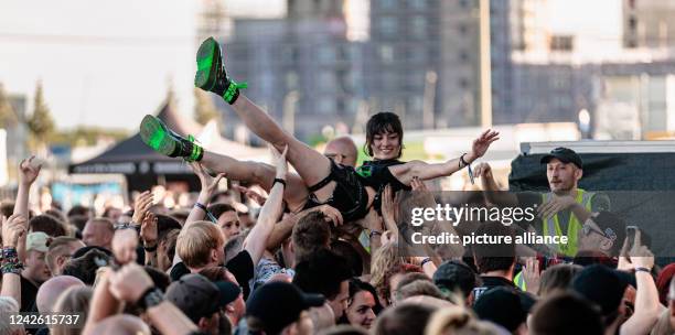 August 2022, Hamburg: Visitors of the metal and rock festival "Elbriot" 2022 move a young woman on her hands towards the stage during crowd surfing....