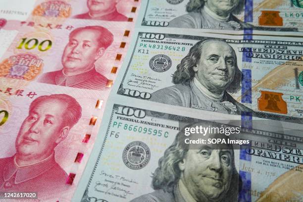 In this photo illustration, 100 US dollar notes and 100 RMB notes seen displayed.