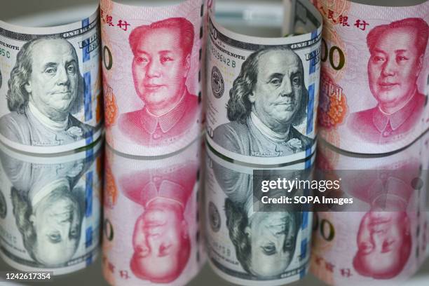 In this photo illustration, 100 US dollar notes and 100 RMB notes seen displayed.