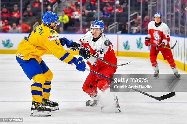 Ivan Ivan of Czechia dumps the puck up the ice as Mans Forsfjall of Sweden moves in for the check during the 2022 IIHF World Junior Championship...