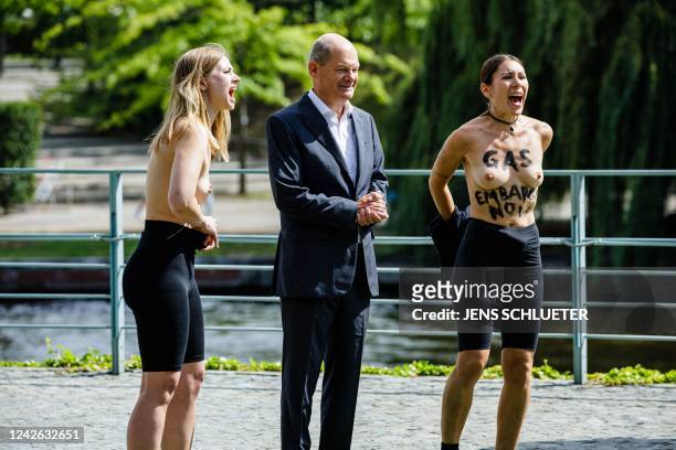 Topless demonstrators with the slogan reading "GAS EMBARGO NOW" on their skin protest beside German Chancellor Olaf Scholz during the Federal...