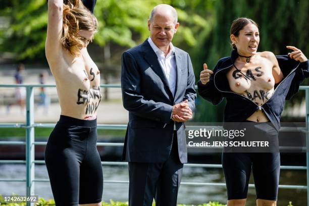 Demonstrators take their shirts off to protest topless with the slogan reading "GAS EMBARGO NOW" on their skin, beside German Chancellor Olaf Scholz...