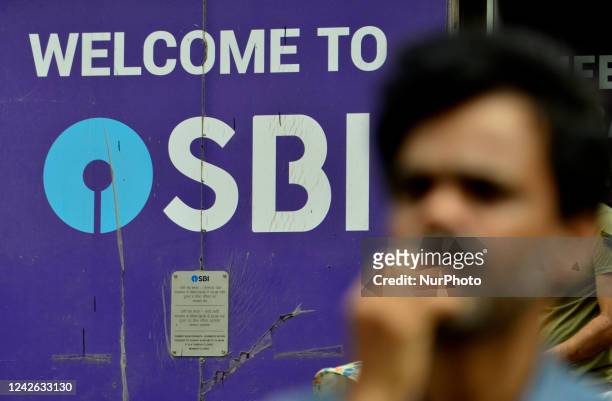 Man stands in front of SBI logo in Mumbai, India, 21 August, 2022.