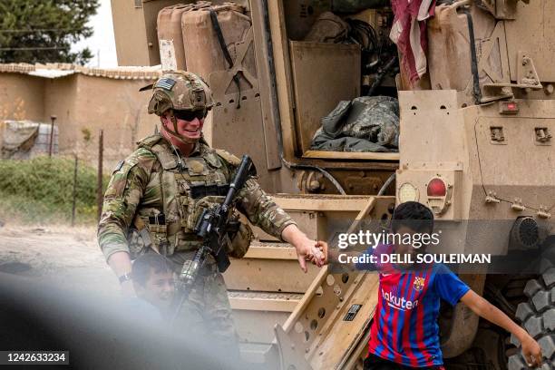 Soldier is pulled by the hand by a boy during a patrol near the Syrian-Turkish border in one of the villages that was subject to bombardment the...