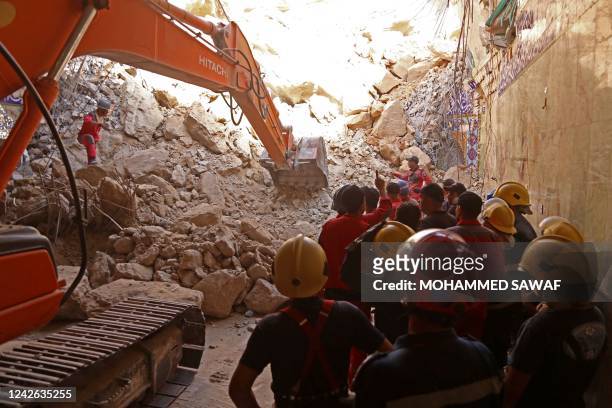 Iraqi rescue workers search for survivors trapped under the rubble of the Qattarat al-Imam Ali shrine following a landslide, on the outskirts of the...
