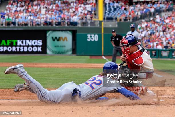 Brett Baty of the New York Mets slides safely into home plate ahead of the tag by catcher J.T. Realmuto of the Philadelphia Phillies on a two-run...