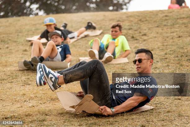 Rob Refsnyder of the Boston Red Sox slides down a hill with fans ahead of the 2022 Little League Classic game against the Baltimore Orioles on August...