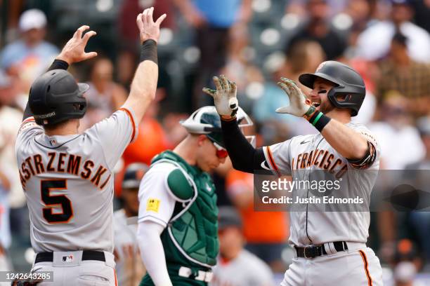 Evan Longoria of the San Francisco Giants is congratulated on his go-ahead grand slam by Mike Yastrzemski as Brian Serven of the Colorado Rockies...