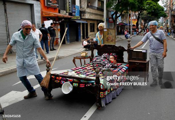 Men push a bed with a woman sleeping on it during the celebration of the World Day of Laziness in Itagui, Colombia, on August 21, 2022.