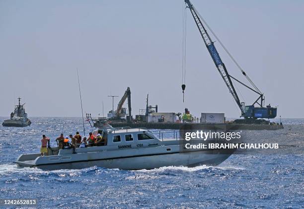 Lebanese Navy boat carrying relatives of victims sails past a launch platform for a submarine operation intended to find and salvage the wreckage of...