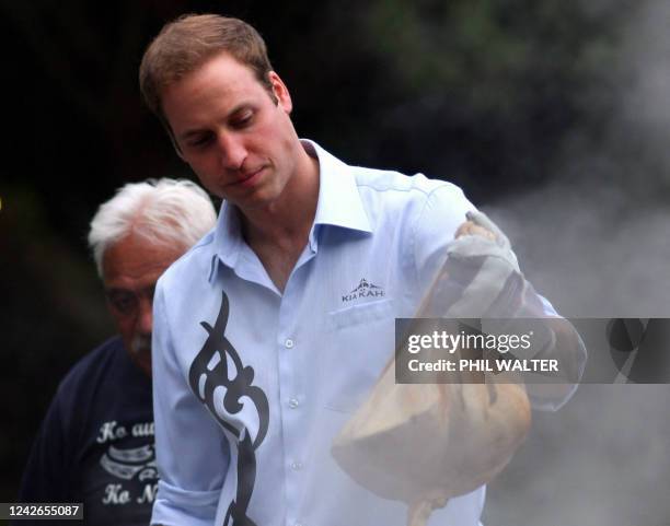 Britain's Prince William lifts a parcel of food out of the traditional Maori earth oven called a 'hangi' at Government House on the first day of his...