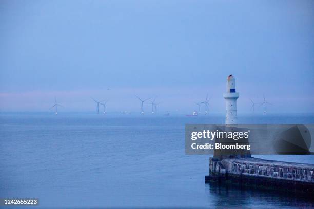 Offshore wind turbines beyond the harbour arm at the Port of Aberdeen sea port at dusk in Aberdeen, UK, on Monday, July 18, 2022. Aberdeen in...